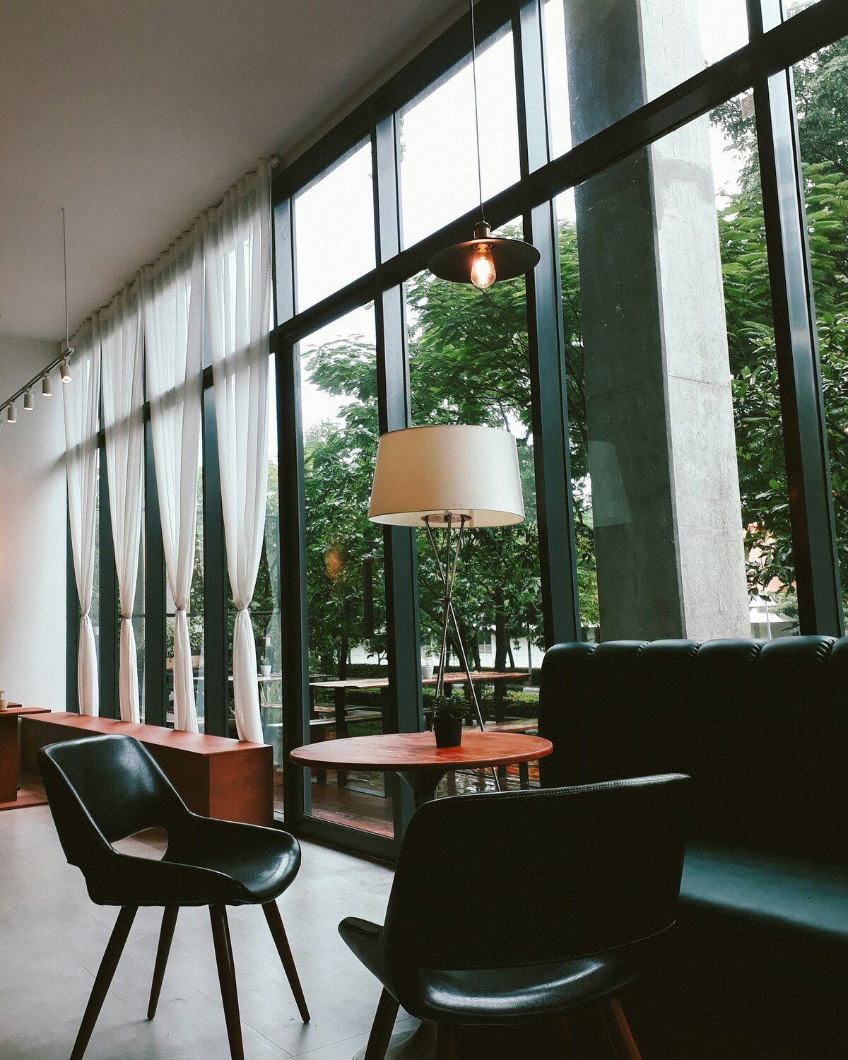 Helle Lounge mit Sesseln, Stehleuchte und bodentiefen Fenstern